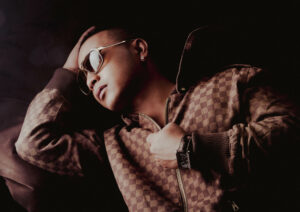 Shooting photo avec Willy Denzey – Portrait intime de l’artiste allongé, capturant son expression relaxée et son style unique dans une lumière tamisée.