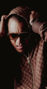 Shooting photo avec Willy Denzey – Un portrait intense capturant l’artiste en pleine interprétation musicale, avec un style affirmé et une lumière cinématographique.
