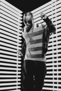Shooting photo avec Willy Denzey lors du tournage de son clip – Un portrait en noir et blanc capturant l’énergie et le charisme de l’artiste dans un décor lumineux.