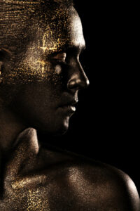 Portrait artistique de Lorie, visage peint en noir avec des touches d’or, réalisé par Yan Forhan, photographe officiel de Lorie Pester, et maquillé par Damien Dufresne pour son livre photo exclusif.